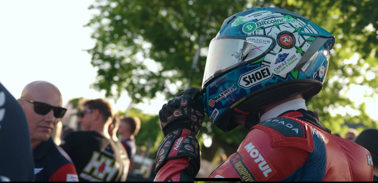 Dean Harrison about to lift his visor, surrounded by people on the Isle of Man